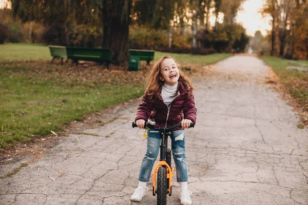 Parkta sonbahar yürüyüşü sırasında bisiklete binen ve neşeyle gülümseyen güzel beyaz kız. — Stok fotoğraf