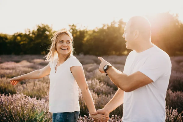 Beautiful woman walking in a lavender field with her caucasian lover who is pointing to something