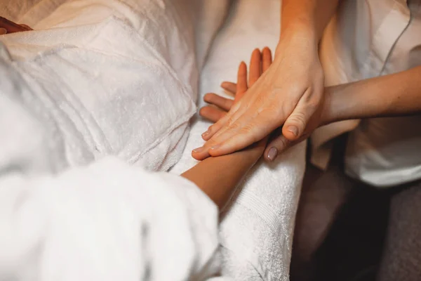 Dermatologista experiente está massageando a mão dos clientes depois de aplicar um creme anti envelhecimento — Fotografia de Stock