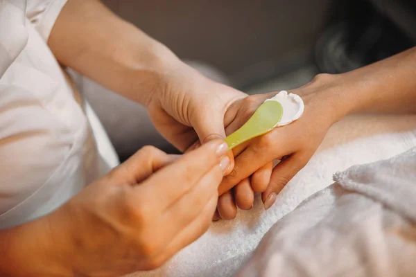 Kaukaski dermatolog używa kremu do rąk po zakończeniu zabiegów anti aging na skórze — Zdjęcie stockowe