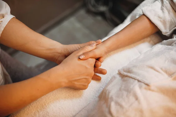 Trabalhador de spa caucasiano massageando a mão dos pacientes e preparando-a para o próximo procedimento — Fotografia de Stock