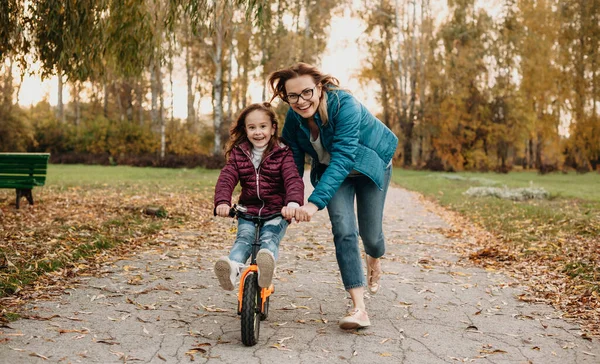 Kafkas annenin, kızının bisiklete binmesine yardım ederken gözlüklerinden baktığı ön manzara. — Stok fotoğraf