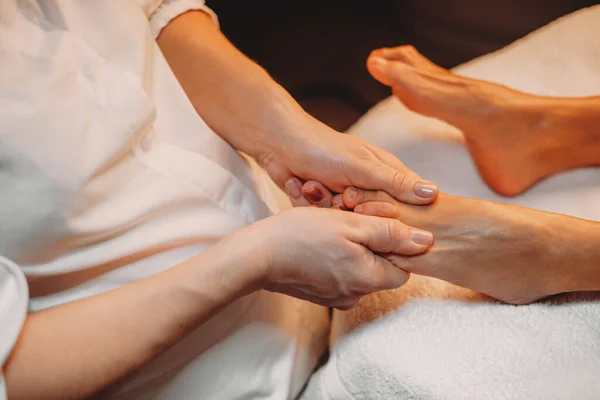 Massagista caucasiano está trabalhando com as pernas dos clientes durante um procedimento de spa no salão — Fotografia de Stock