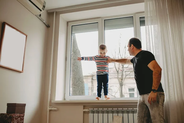 Attento padre caucasico che tiene per mano i suoi figli che è seduto vicino alla finestra — Foto Stock