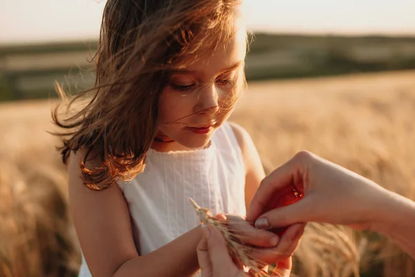 Charmant roodharig blank meisje met tarwezaden poserend in een veld bij haar moeder — Stockfoto