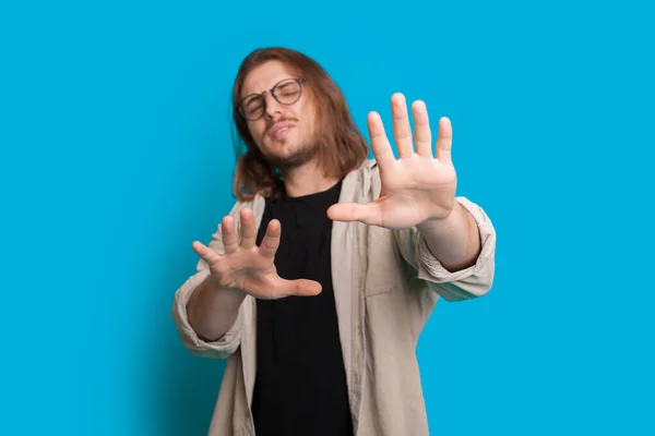 Homem caucasiano com cabelos longos e barba está se recusando a algo enquanto posando em um fundo azul — Fotografia de Stock