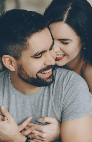 Fröhliche kaukasische Brünette umarmt ihren bärtigen Liebhaber, während sie lächelt und zusammen Spaß hat — Stockfoto