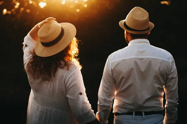 L'homme caucasien et sa charmante femme en surpoids portant une robe blanche et un chapeau posent contre le coucher du soleil — Photo