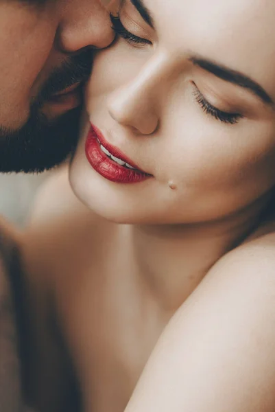 Stunning caucasian girl with red lips is kissed by her bearded lover while embracing each other — Stock Photo, Image