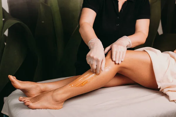 Καυκάσια κυρία με όμορφα πόδια έχει μια ζάχαρη αποτρίχωση κατά τη διάρκεια μιας επαγγελματικής διαδικασίας spa — Φωτογραφία Αρχείου
