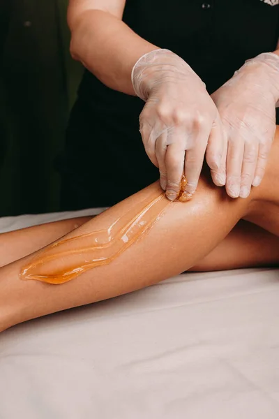 Sugaring procedimento em pernas feitas por um especialista spa durante um procedimento no salão — Fotografia de Stock