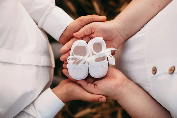 Υπέροχο ζευγάρι Καυκάσιος κρατώντας ένα ζευγάρι παπούτσια μωρό, ενώ ποζάρουν κοντά το ένα στο άλλο — Φωτογραφία Αρχείου