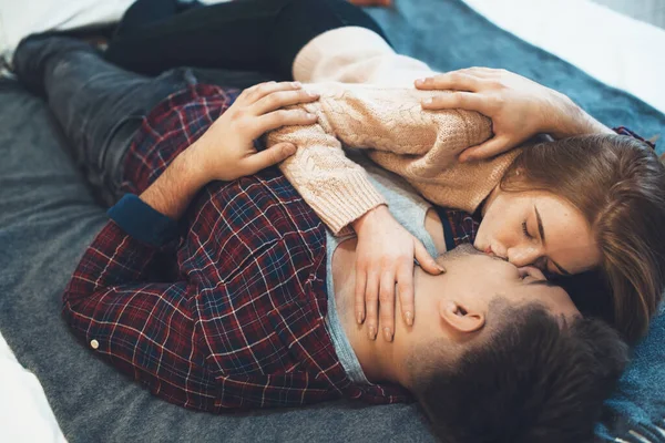 Charming caucasian woman lying in bed with her lover while embracing and kissing each other — Stock Photo, Image