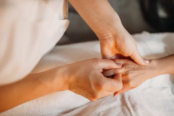 Jovem massagista está massageando dedos femininos para torná-los relaxados após sessões de spa — Fotografia de Stock