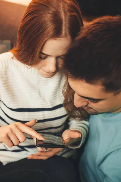 Rousse cheveux caucasien fille avec taches de rousseur embrassé par son amant est à la recherche de quelque chose dans son téléphone mobile — Photo