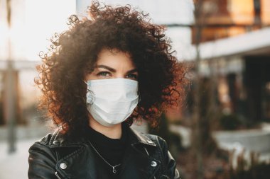 Güzel kıvırcık saçlı beyaz bir kız tarafından izole edilmiş. Kameraya bakarken üzgün bir şekilde dışarıda poz veriyor.