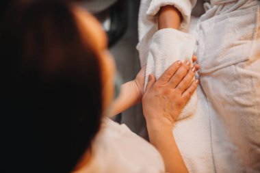 Kafkas spa çalışanı müşterilerin elini havluyla kurutuyor.