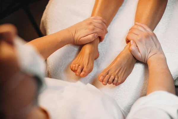 Massagista cuidadoso está reunindo as pernas dos clientes durante um procedimento de cuidados com a pele spa — Fotografia de Stock
