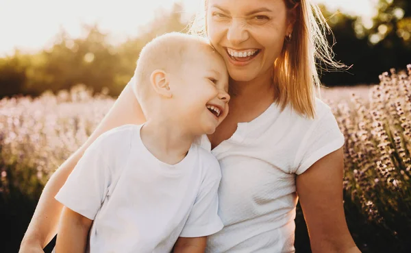 Okouzlující běloška matka hrát se svým synem s levandulovým polem na pozadí — Stock fotografie