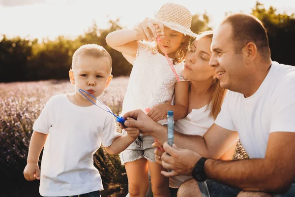 Okouzlující bělošská rodina pózuje na levandulovém poli, zatímco spolu dělají balónky — Stock fotografie