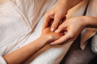 Kafkas spa çalışanı, spa seansı sırasında müşterilerin eline masaj yapıyor.