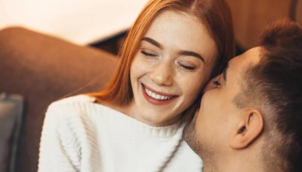 Ginger caucasian lady with freckles is cheering with her love while embracing on a sofa — Stock Photo, Image