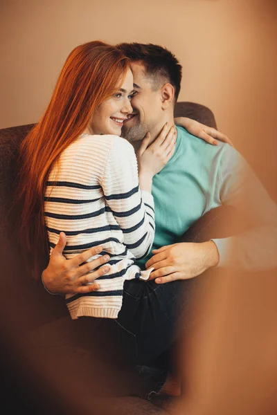 Menina de cabelos vermelhos lindo com sardas é abraçado por seu amante, tendo alegria juntos em um sofá — Fotografia de Stock
