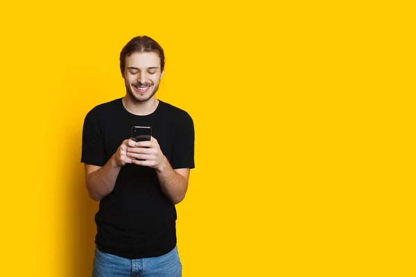 Homem caucasiano de cabelos compridos conversando com alguém no telefone está sorrindo em um fundo amarelo com espaço livre — Fotografia de Stock