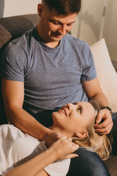 Photo verticale d'une fille caucasienne blonde allongée sur les genoux de ses amants tout en discutant et en ayant de beaux moments ensemble — Photo