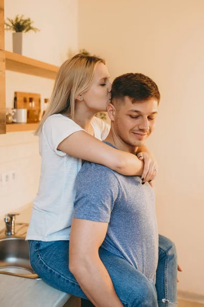 Encantadora señora rubia caucásica abrazando a su amante y besándolo en la cocina —  Fotos de Stock