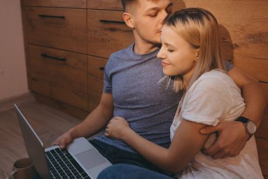 Dikkatli ol, beyaz adam laptopla çay içerken sarışın karısını öpüyor.