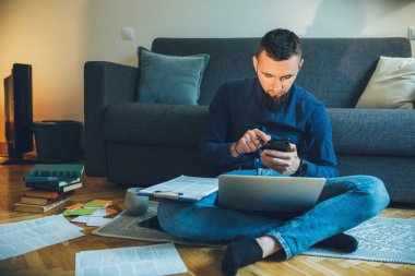 Genç beyaz girişimci, karantina nedeniyle bazı belgelerle evde çalışıyor.