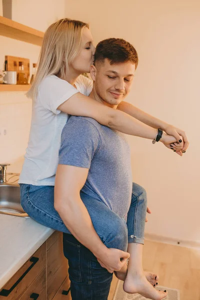 Affascinante ragazza bionda che abbraccia il suo amante caucasico mentre lo bacia in cucina — Foto Stock