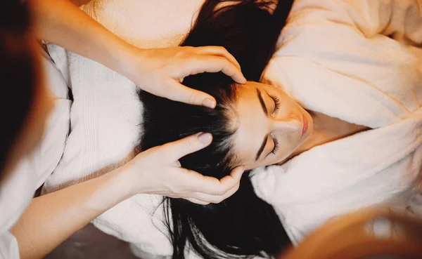 Visão superior retrato de uma mulher morena caucasiana deitada no sofá enquanto faz uma sessão de massagem na cabeça — Fotografia de Stock
