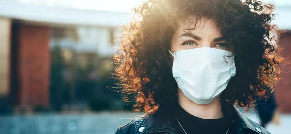 Close up portrait caucasian business woman with curly hair is looking at camera while wearing a protective mask — Stok Foto
