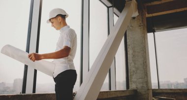 Kafkasyalı genç adam miğfer takarken haritayı analiz ediyor.