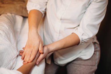 Kafkasyalı bir masörün müşteriyle el masajı yaparken üst görüntüsü.