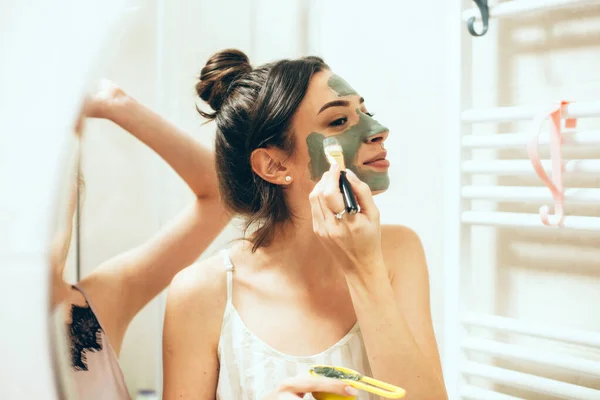 Spiegelbeeld van een brunette dame toepassen van een speciaal masker op haar gezicht staan in de buurt van haar vriend — Stockfoto