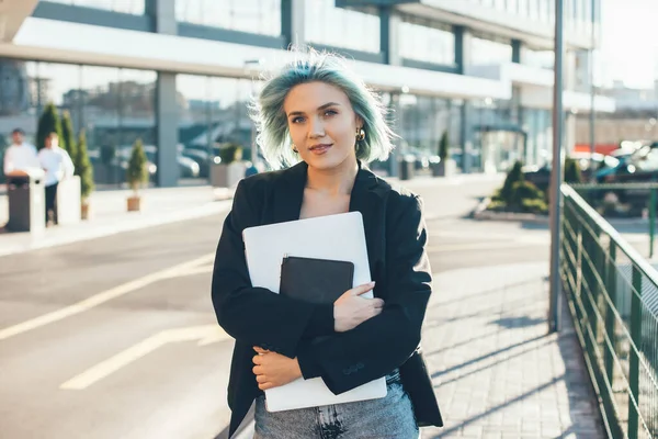 Piękny biały freelancer z niebieski włosy pozowanie z a komputer podczas patrząc w kamera — Zdjęcie stockowe