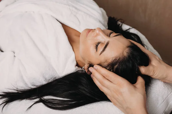 Mulher branca morena com massagem na cabeça no salão durante um procedimento de spa — Fotografia de Stock