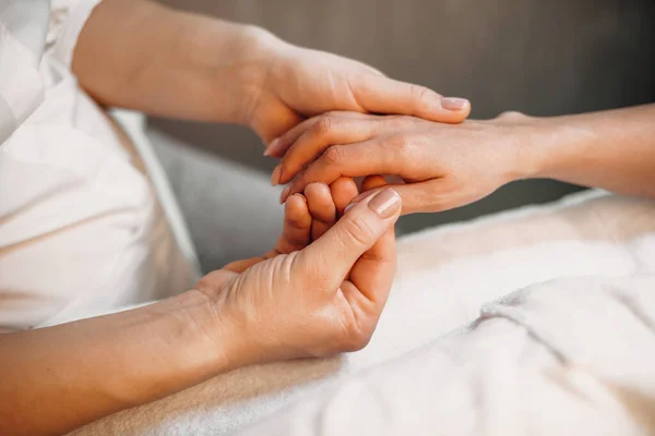 Massagista caucasiano cuidadoso massagear os clientes mão e dedos durante um procedimento de spa — Fotografia de Stock