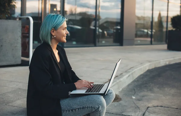 Mavi saçlı kadın sokakta oturmuş bilgisayarın başında poz veriyor. — Stok fotoğraf