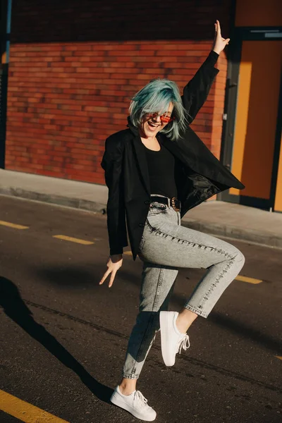 Estudiante caucásico con pelo azul bailando en la calle mientras usa gafas de sol rojas — Foto de Stock