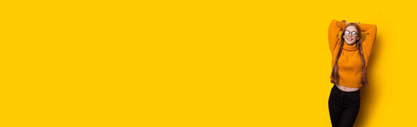 Монохромное фото рыжей кавказки с веснушками и стаканами, позирующими руками на желтой стене с свободным пространством
