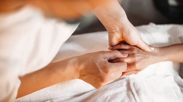 Trabalhador de spa caucasiano massajando os dedos dos clientes durante um procedimento de massagem manual no salão de spa — Fotografia de Stock
