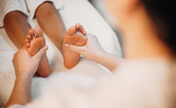 Upper view photo of leg massage session done at the spa salon to the lying on the couch client