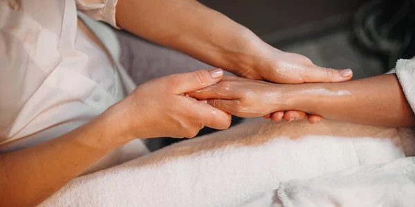 Sesja masażu ręcznego ze specjalnym kremem w salonie spa dla młodej kobiety — Zdjęcie stockowe