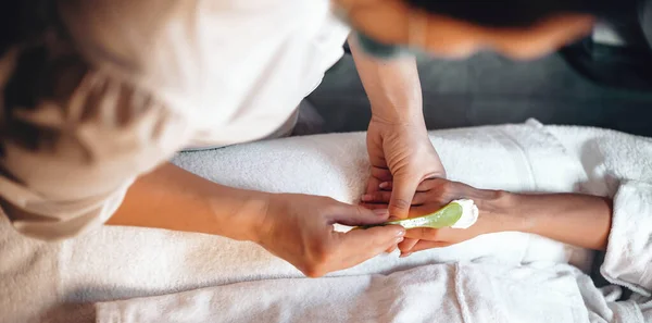 Massagista caucasiano aplicando creme especial antes de iniciar a sessão de massagem no salão de spa — Fotografia de Stock