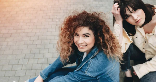 Lässig gekleidete Frauen gehen zusammen und posieren in einer Straße und blicken in die Kamera — Stockfoto