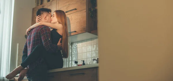 Menina caucasiana com cabelos vermelhos e sardas é ebracing seu amante na cozinha — Fotografia de Stock